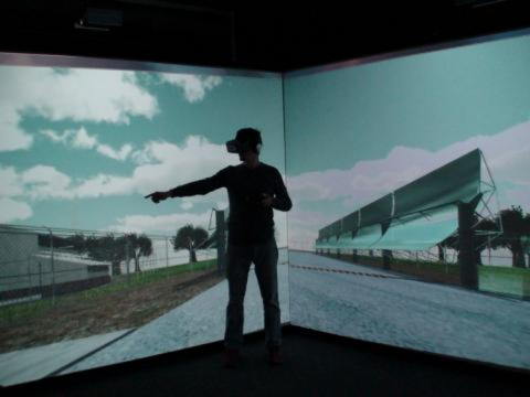 Student with a VR headset standing in front of a projected scene from the solar fields